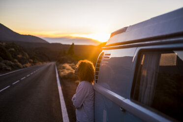 Spanien, Teneriffa, nachdenkliche Frau bei Sonnenuntergang, die sich an einen am Straßenrand geparkten Lieferwagen lehnt - SIPF01756