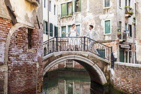 Italien, Venedig, Brautpaar läuft auf kleiner Brücke, lizenzfreies Stockfoto