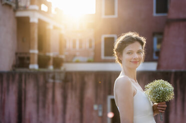 Italien, Venedig, Porträt einer lächelnden Braut mit Brautstrauß bei Sonnenaufgang - DIGF02855