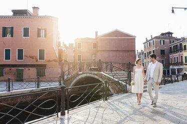Italien, Venedig, Brautpaar geht Hand in Hand bei Sonnenaufgang - DIGF02861