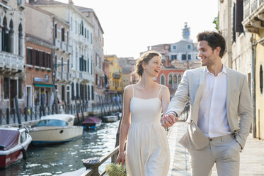 Italien, Venedig, glückliches Brautpaar geht Hand in Hand in der Morgendämmerung - DIGF02867
