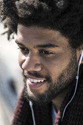 Portrait of smiling man listening to music on his earphones - SBOF00674