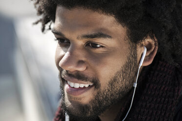 Portrait of smiling man listening to music on his earphones - SBOF00676
