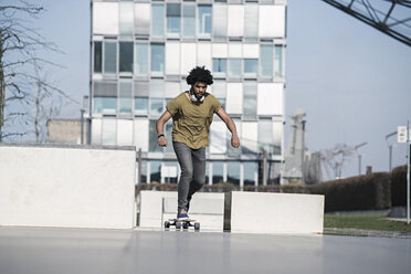 Young man riding longboard in skatepark - SBOF00694