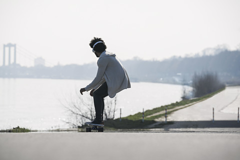 Young man riding longboard at the riverside stock photo