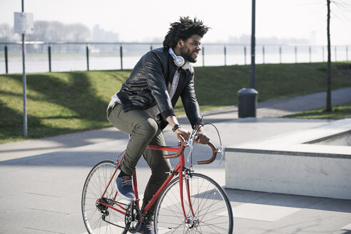 Lächelnder Mann beim Fahrradfahren am Flussufer - SBOF00699