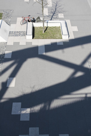 Mann entspannt sich im städtischen Skatepark mit Smartphone neben seinem Fahrrad, lizenzfreies Stockfoto