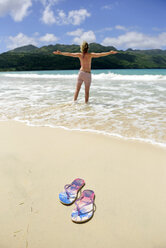 Dominikanische Republik, Samana, Flip-Flops am Strand und Frau im Meer - ECPF00113
