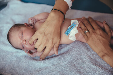 Neugeborenes Mädchen liegt auf einem Handtuch und saugt am Finger der Mutter - MFF03977