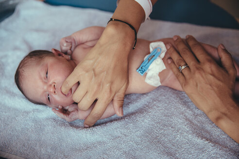 Neugeborenes Mädchen liegt auf einem Handtuch und saugt am Finger der Mutter - MFF03977