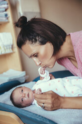 Mutter küsst die Hand ihres neugeborenen Mädchens im Krankenhauszimmer - MFF03978