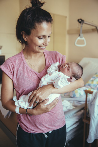 Glückliche Mutter hält ihr neugeborenes Baby im Krankenhaus, lizenzfreies Stockfoto