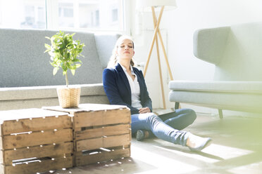 Businesswoman sitting on the floor relaxing - JOSF01749