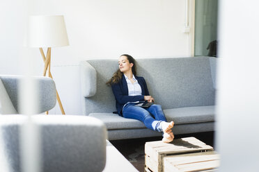 Businesswoman sitting on couch relaxing - JOSF01750