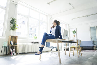 Businesswoman sitting on table in a loft - JOSF01758