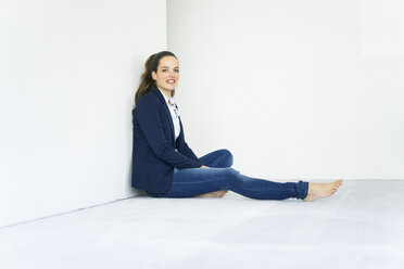 Portrait of businesswoman sitting on the floor - JOSF01782