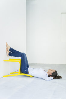 Frau auf dem Boden liegend mit einem gelben Stuhl - JOSF01787