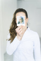 Woman covering her face with instant photo of herself - JOSF01788