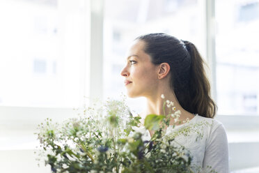 Frau mit Blumen schaut aus dem Fenster - JOSF01803