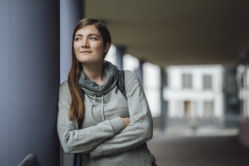 Porträt einer lächelnden jungen Frau, die sich an eine Säule lehnt und in die Ferne schaut - JSCF00002