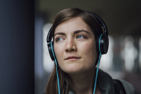 Portrait of daydreaming young woman listening music with headphones - JSCF00005