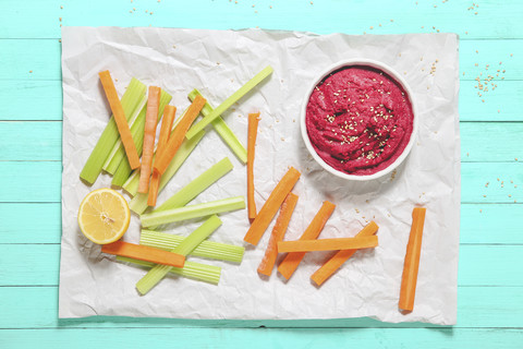 Bowl of beetroot hummus, sesame, and carrot and celery crudites stock photo