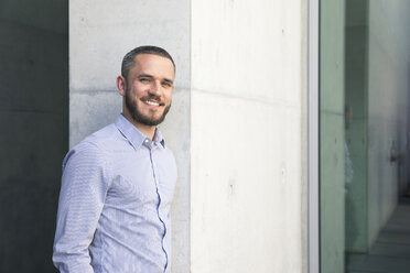 Portrait of smiling businessman at a wall - FKF02526