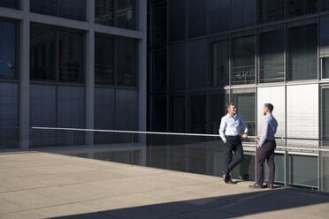 Two businessmen talking outside office building - FKF02534