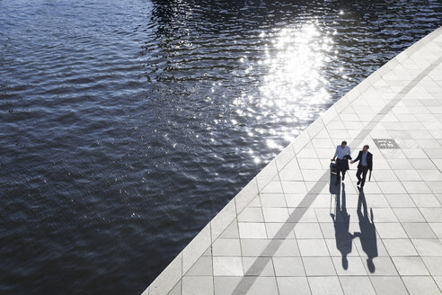 Two businessmen walking and talking at the riverbank - FKF02536