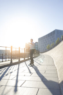 Geschäftsmann fährt Skateboard in der Stadt - FKF02542