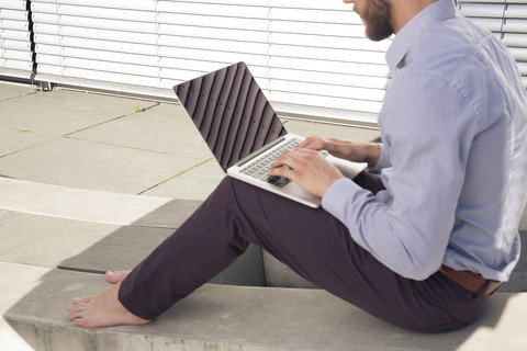 Barfüßiger Geschäftsmann benutzt Laptop im Freien, lizenzfreies Stockfoto