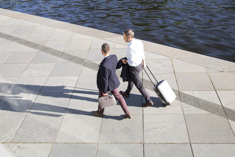 Zwei Geschäftsleute, die am Flussufer spazieren gehen und sich unterhalten, lizenzfreies Stockfoto