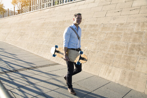 Geschäftsmann zu Fuß mit Skateboard - FKF02592