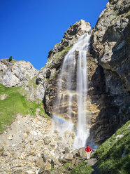 Italy, South Tyrol, hiker at waterfall on path towards Schlinig Pass - LAF01895