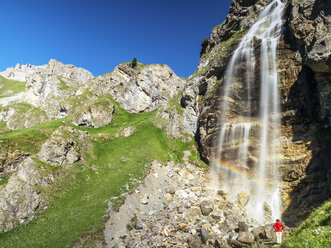 Italy, South Tyrol, hiker at waterfall on path towards Schlinig Pass - LAF01896
