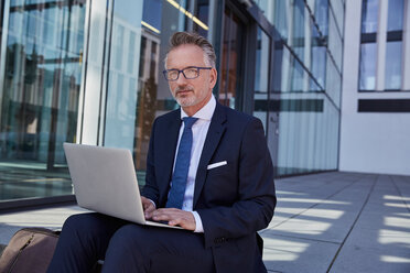 Portrait of businessman using laptop outdoors - SUF00286