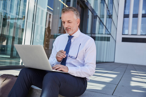 Portrait of businessman using laptop outdoors stock photo