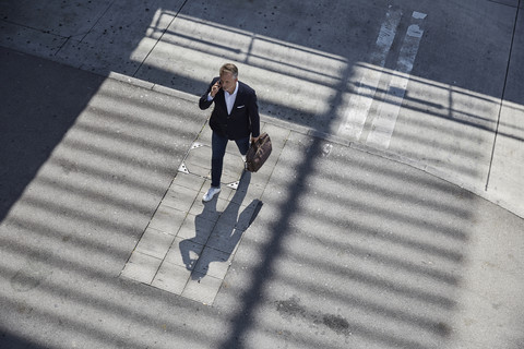 Geschäftsmann beim Telefonieren auf dem Bürgersteig, Draufsicht, lizenzfreies Stockfoto