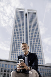 Grauhaariger Geschäftsmann vor einem Wolkenkratzer mit Kaffee zum Mitnehmen - SBOF00744