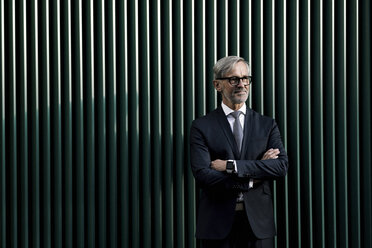 Portrait of grey-haired businessman in front of green wall - SBOF00749