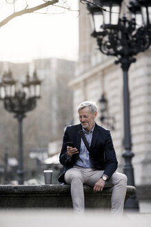 Grauhaariger Geschäftsmann in der Stadt mit Smartphone und Kaffee zum Mitnehmen - SBOF00766