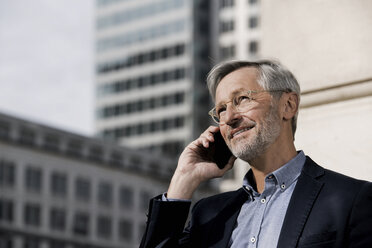 Grauhaariger Geschäftsmann mit Smartphone in der Stadt - SBOF00767