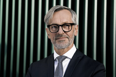 Portrait of grey-haired businessman in front of green wall - SBOF00789