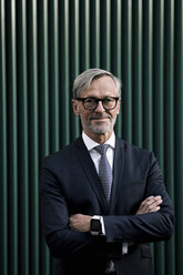 Porträt eines selbstbewussten grauhaarigen Geschäftsmannes vor einer grünen Wand - SBOF00790