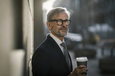 Grey-haired businessman in the city holding coffee to go - SBOF00792