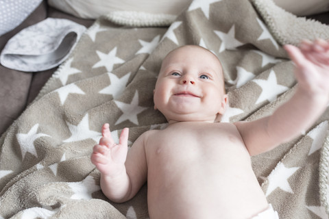 Portrait of happy baby girl lying on a blanket stock photo
