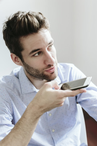 Junger Geschäftsmann arbeitet im Büro und benutzt sein Smartphone, lizenzfreies Stockfoto