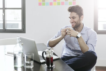 Young businessman sitting at desk with pot of coffee - GIOF03261