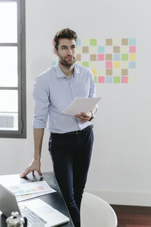 Young businessman working in office, holding documents - GIOF03264