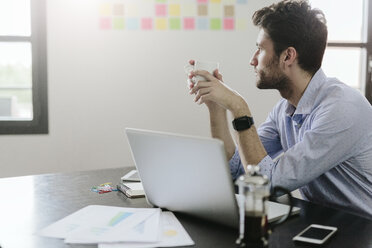 Young businessman working in office, drinking coffee - GIOF03275